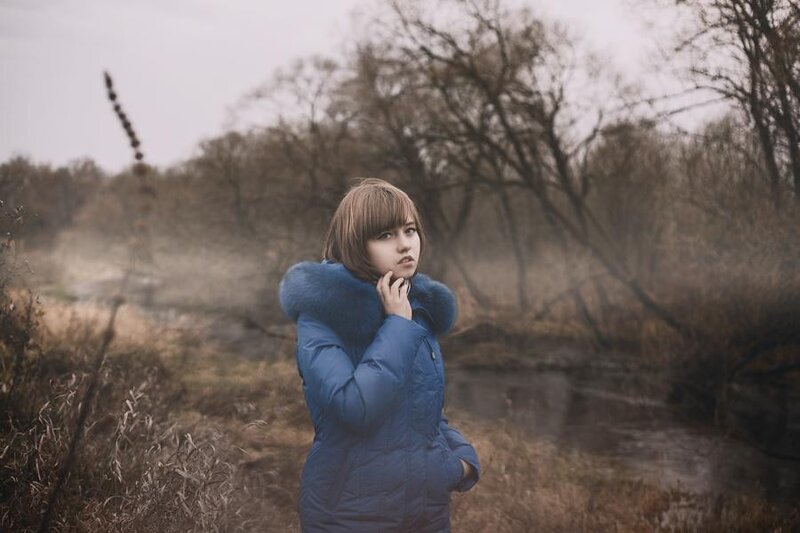 woman in blue coat by river
