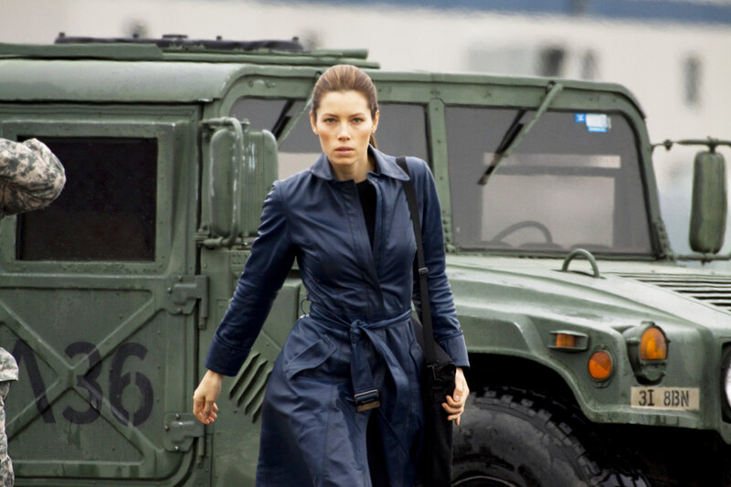 Woman in blue coat near military vehicle