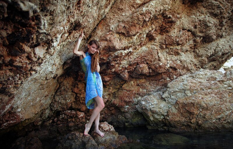 Woman in blue dress at rocky shore