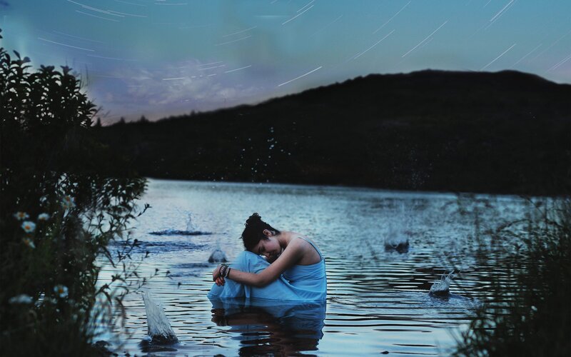 Woman in blue dress by lake