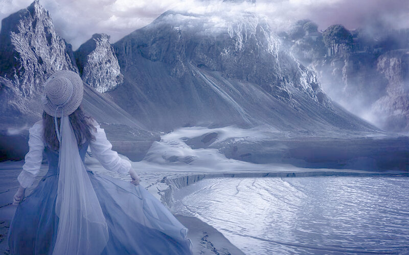 woman in blue dress by mountain lake