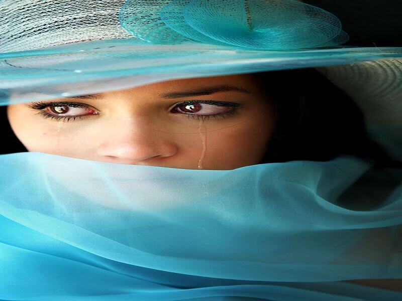 woman in blue hat crying