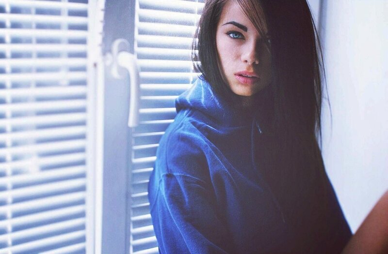 woman in blue hoodie by window