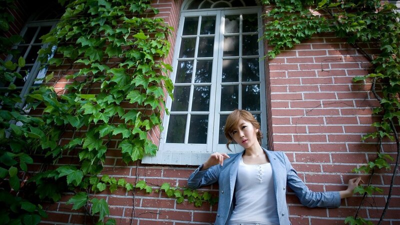 woman in blue jacket by brick wall