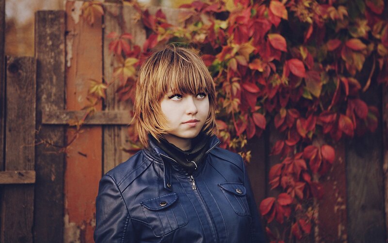 woman in blue jacket with autumn leaves