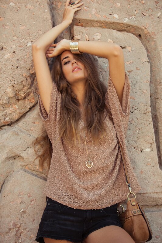 woman in boho top leaning on wall