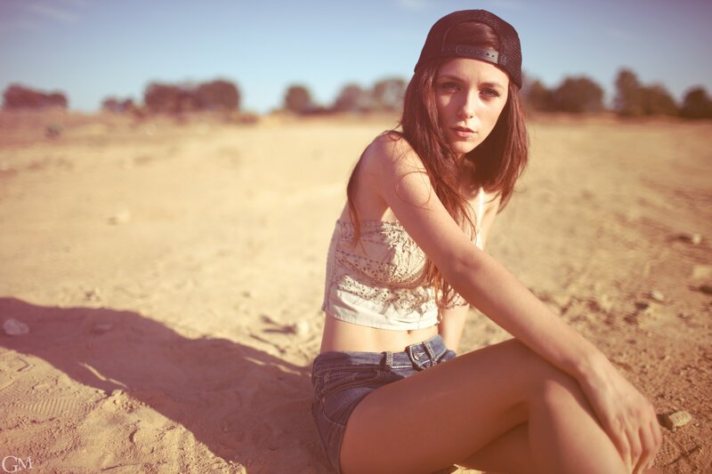 woman in cap sitting on sand