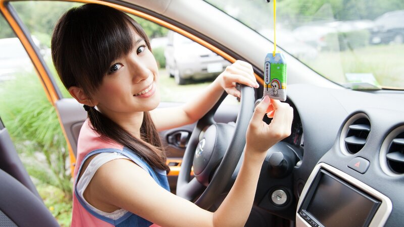 woman in car holding air freshener