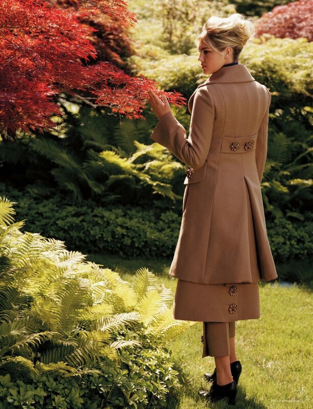 Woman in coat touching red leaves