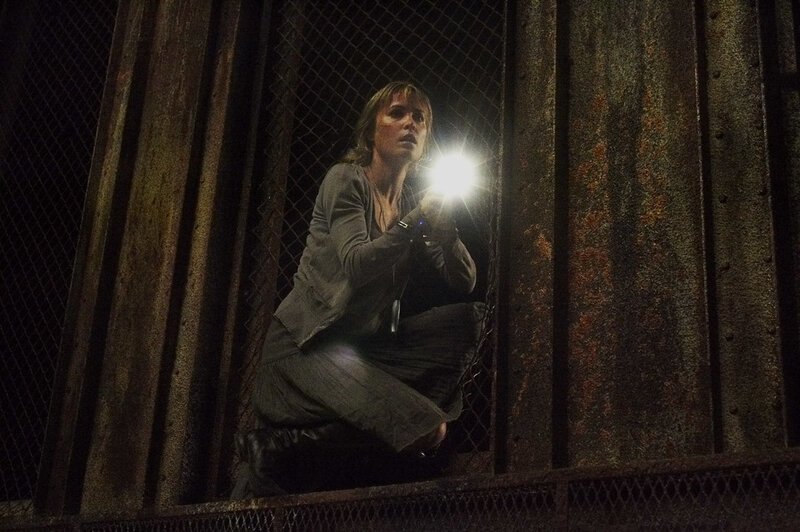 woman in dark cage with flashlight