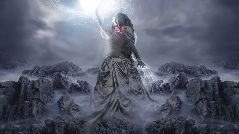 woman in dark dress on rocky shore