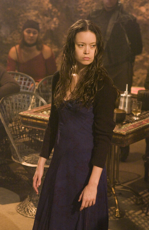Woman in dark dress stands in room