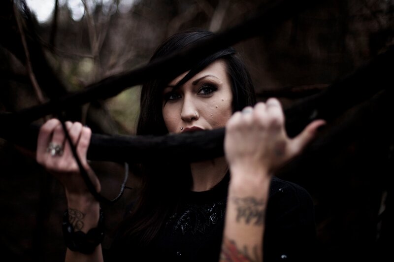 woman in dark forest holding branch