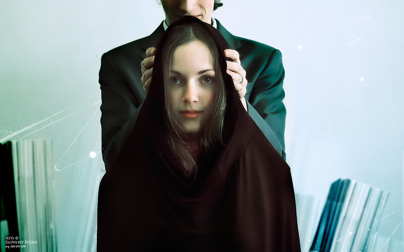 woman in dark hood with man behind