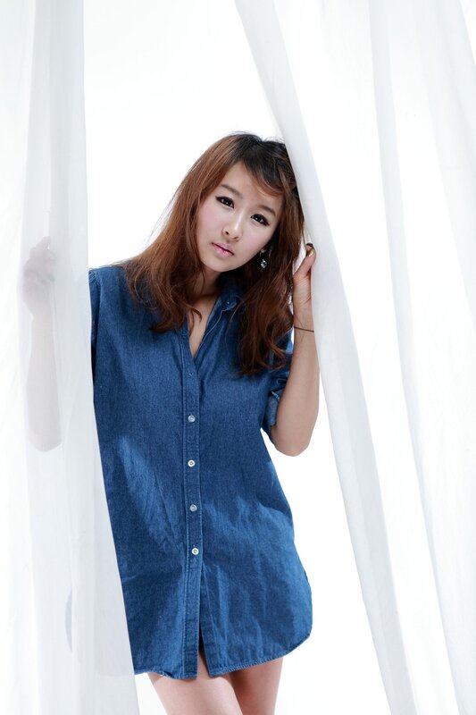 woman in denim dress behind curtain