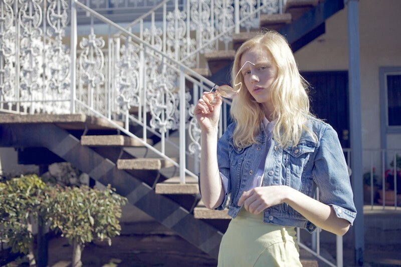 Woman in denim jacket holding sunglasses