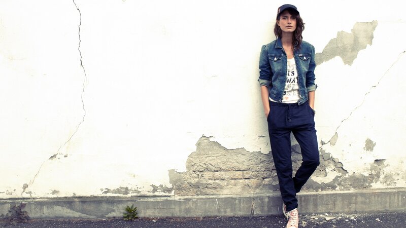 woman in denim jacket leaning on wall