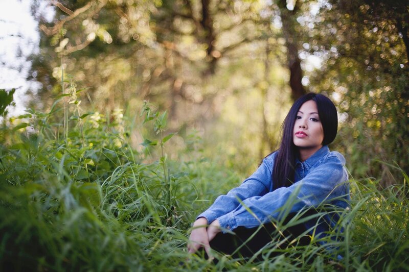 Woman in denim jacket sitting in grass