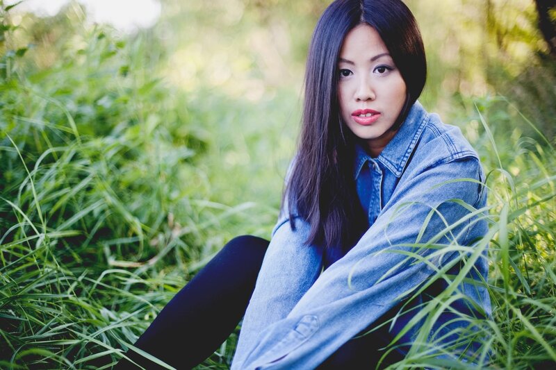 woman in denim jacket sitting in grass