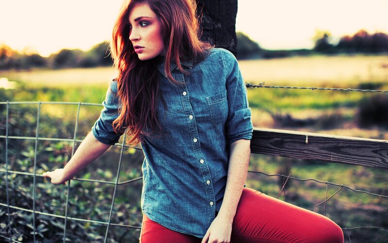 woman in denim shirt by fence