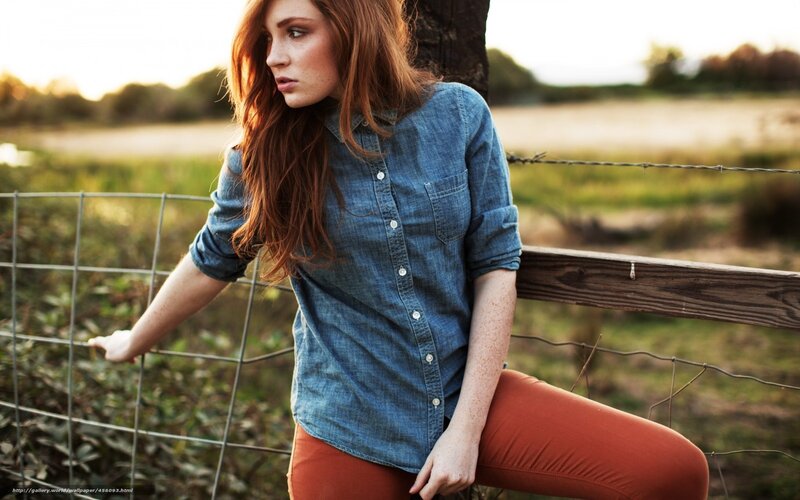 woman in denim shirt by fence