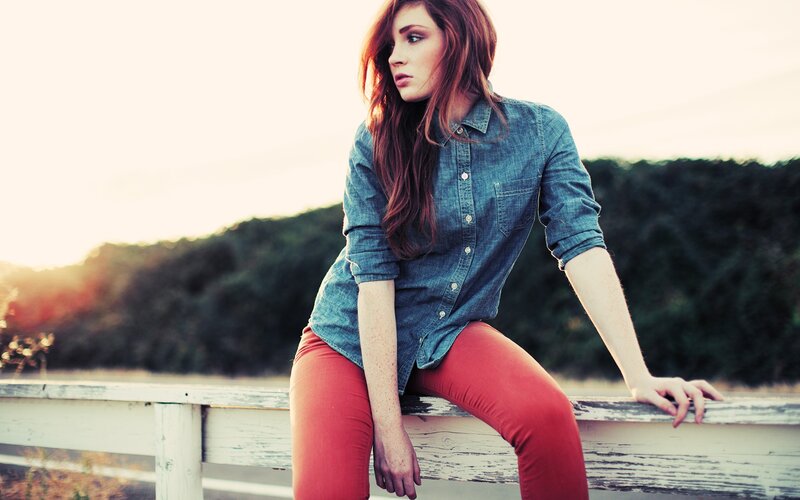woman in denim shirt sitting on fence