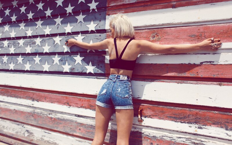 Woman in denim shorts by flag wall