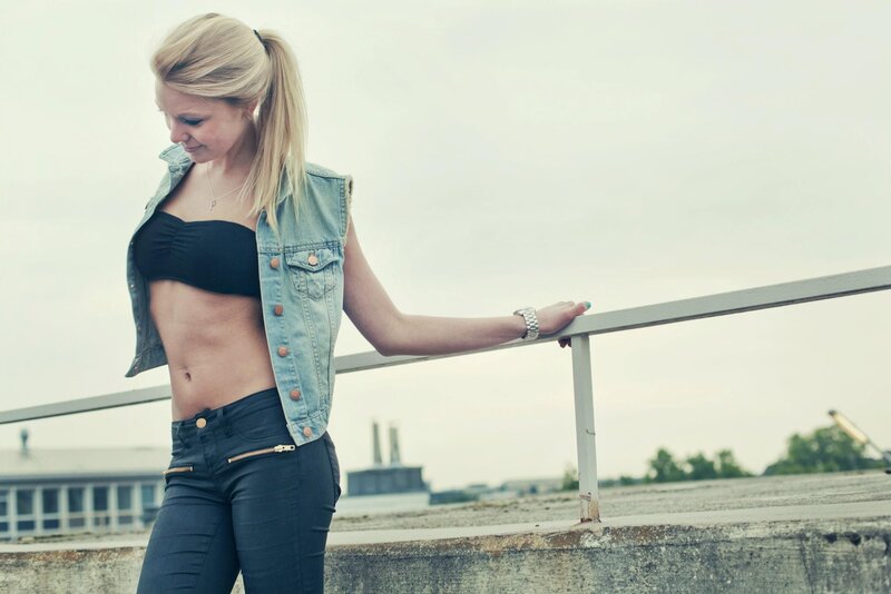 woman in denim vest on rooftop