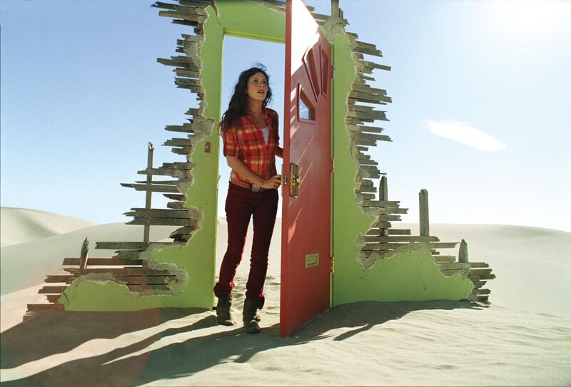 woman in desert with red door