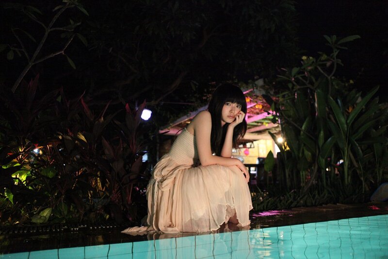 woman in dress by pool at night