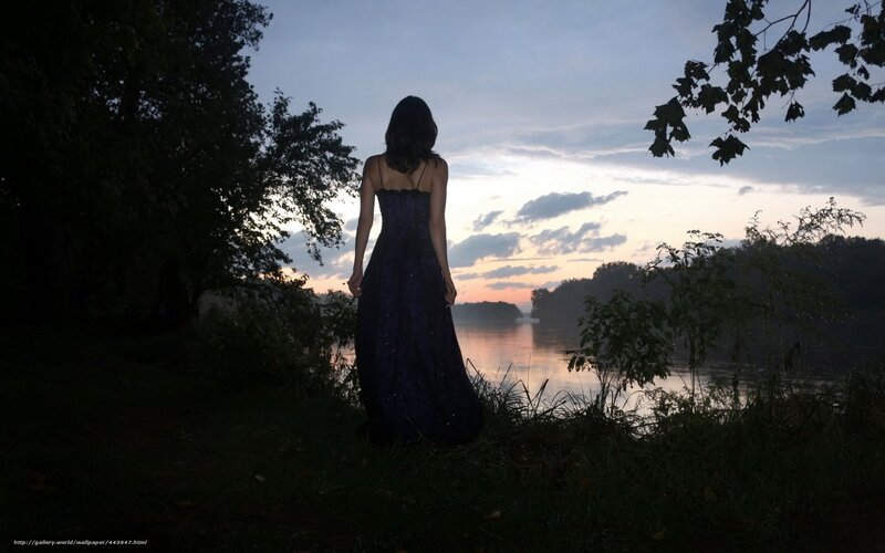 Woman in dress by river at dusk