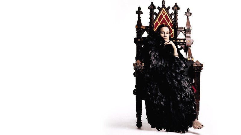 woman in feathered gown on throne