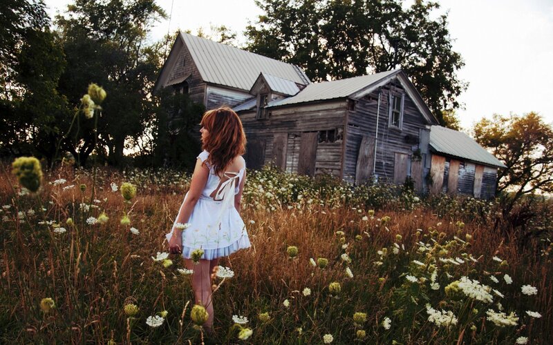 Woman in field near old house