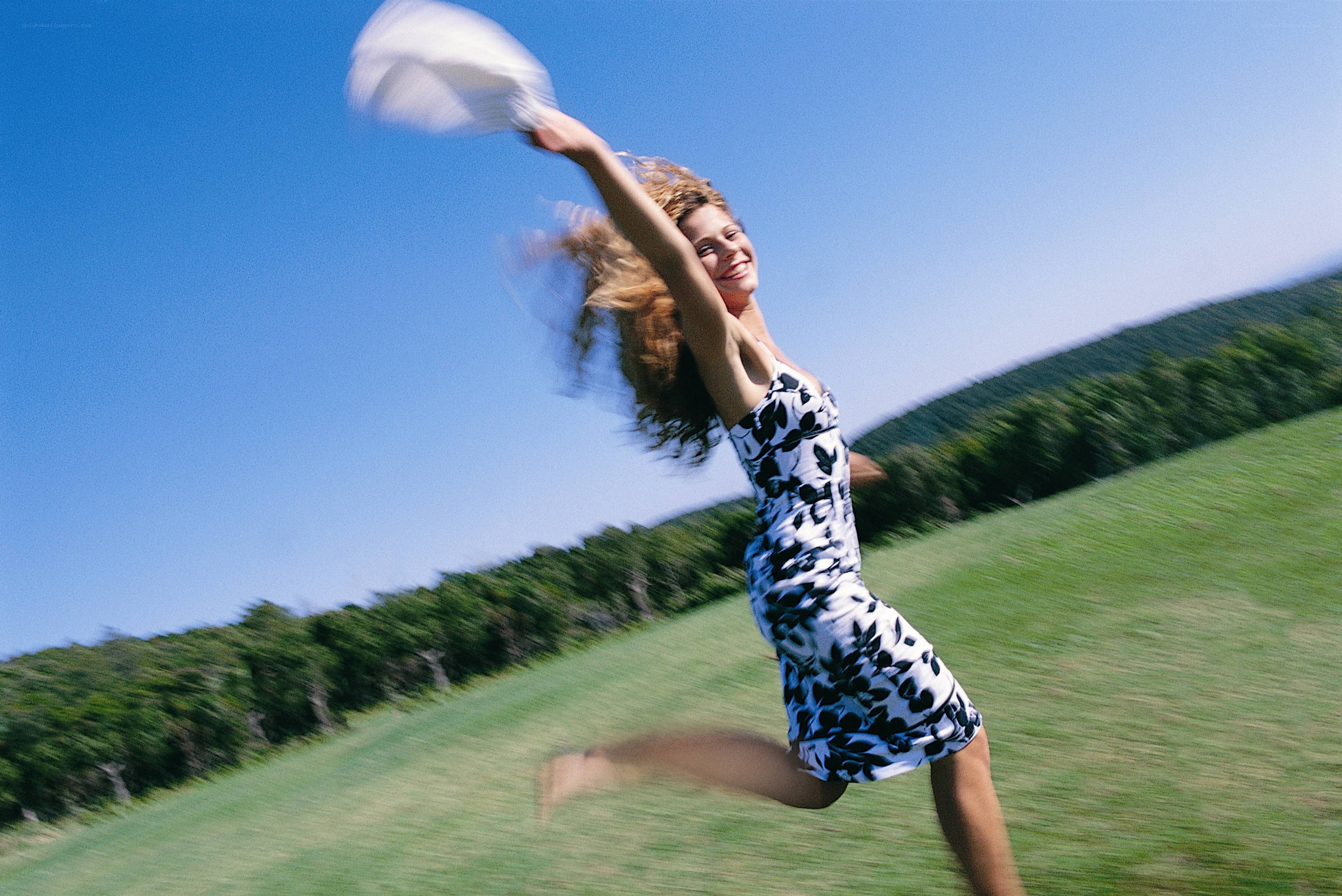 woman in field throwing hat