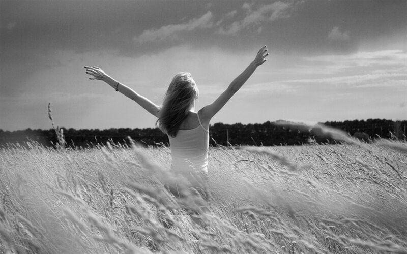 woman in field with arms raised