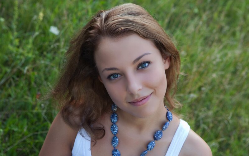 woman in field with blue necklace
