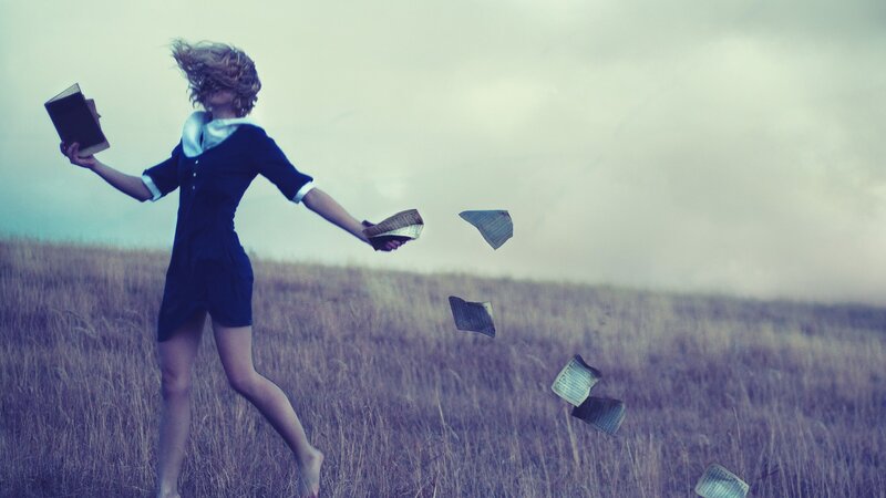 woman in field with books