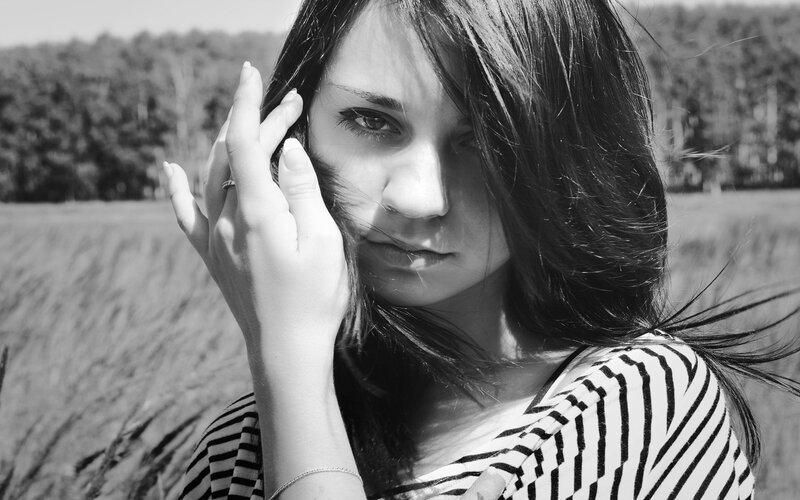 woman in field with hand to face