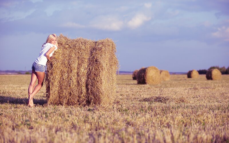 Woman in field with hay bale