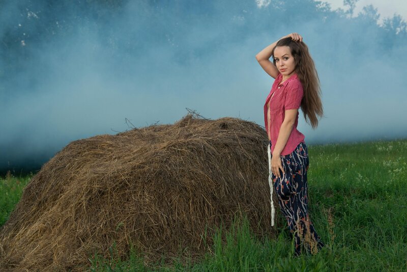 Woman in field with hay bale