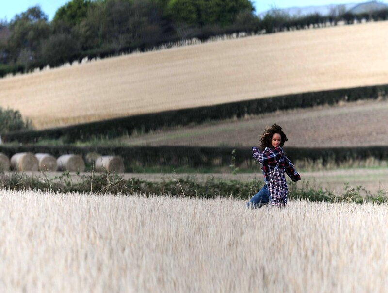 woman in field with hay bales