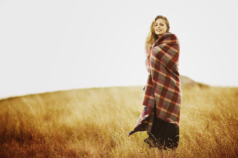 woman in field with plaid blanket