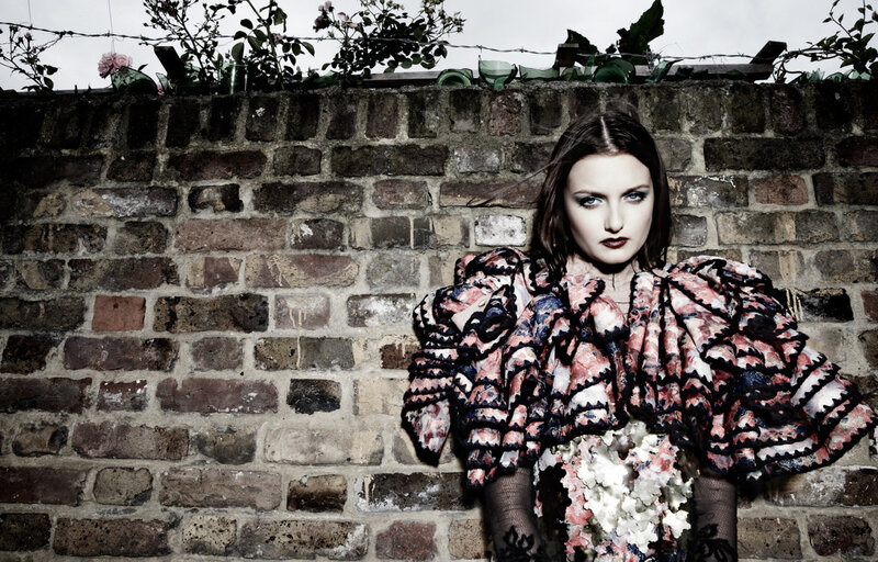 woman in floral dress against brick wall