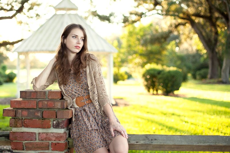 woman in floral dress by brick wall