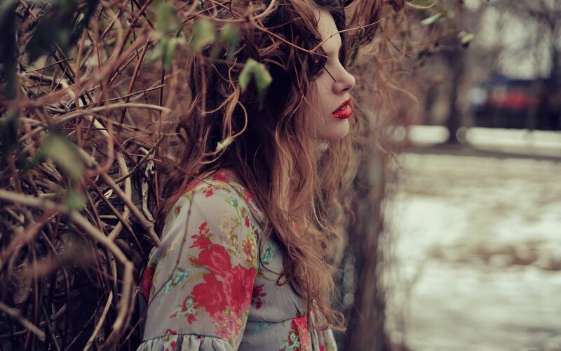 woman in floral dress by bushes