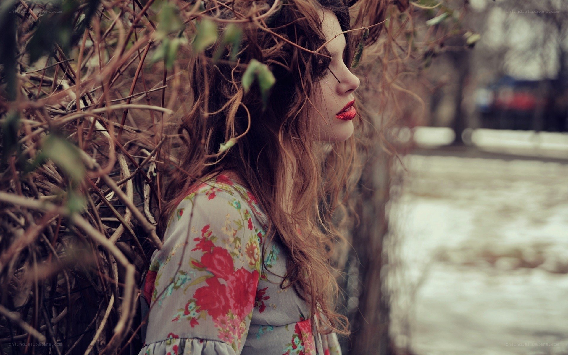 woman in floral dress by bushes