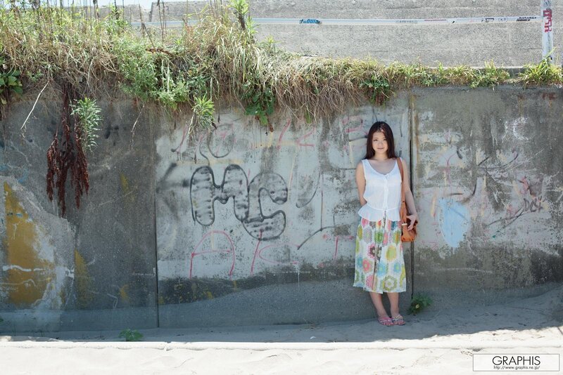 Woman in floral dress by graffiti wall