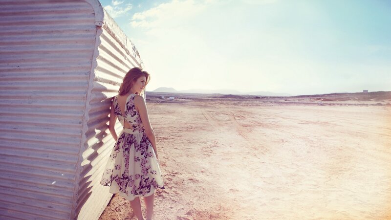 woman in floral dress by shed