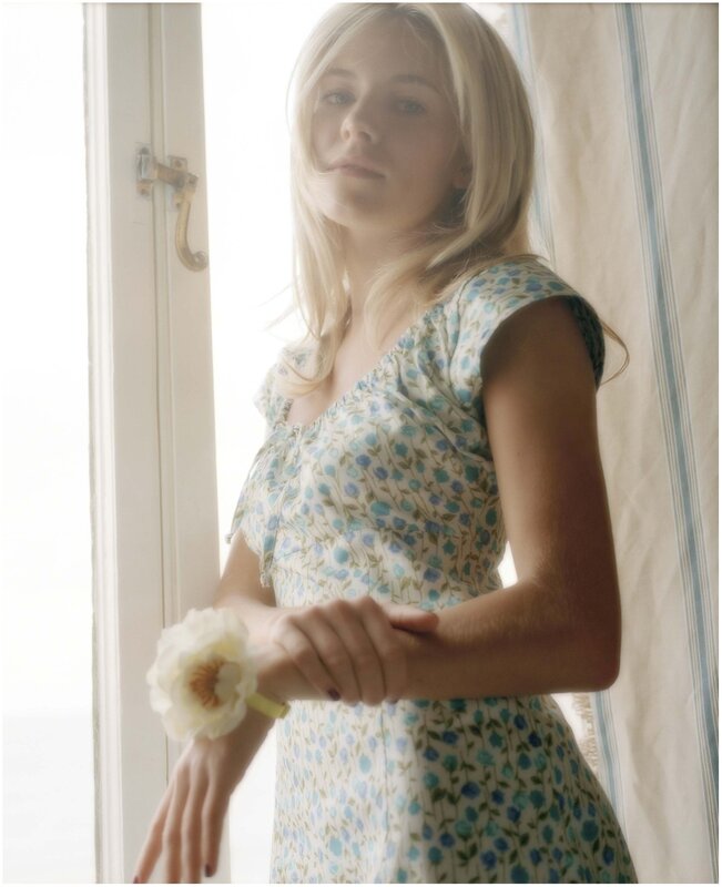 woman in floral dress by window