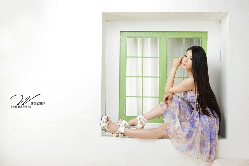 woman in floral dress by window
